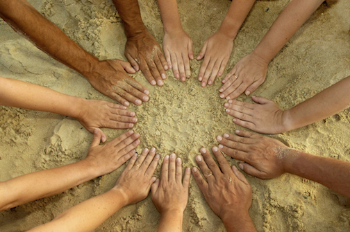 hands in circle on sand
